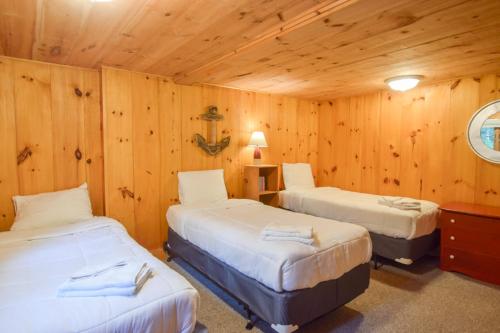 three beds in a room with wooden walls at Steps to Freshwater Beach Kayaks Sauna in Brewster