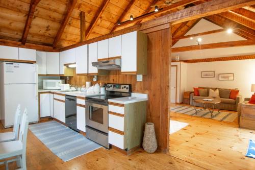 a kitchen and living room with wooden ceilings at Steps to Freshwater Beach Kayaks Sauna in Brewster