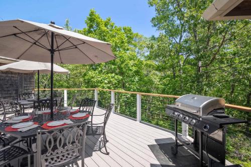a patio with a grill and tables and chairs on a deck at Steps to Freshwater Beach Kayaks Sauna in Brewster