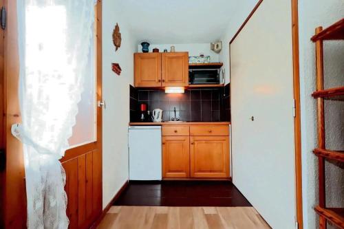 Elle comprend une petite cuisine avec des placards en bois et un réfrigérateur blanc. dans l'établissement Résidence Le Prarion 2 C - Prarion 2 28 MAE-6429, aux Houches