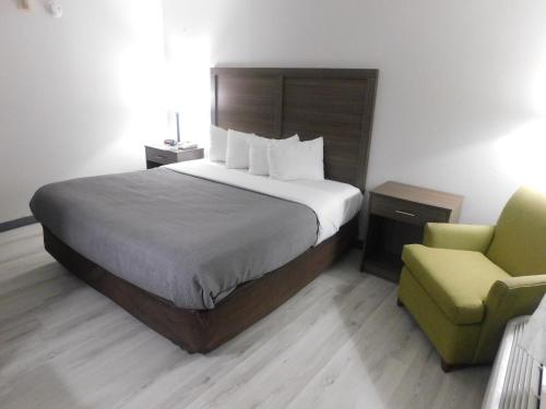 a hotel room with a bed and a chair at Quality Inn & Suites Hanes Mall in Winston-Salem