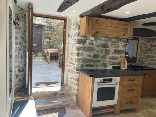 a kitchen with a stove and a stone wall at Gîte dans maison ardéchoise de caractère in Beaumont