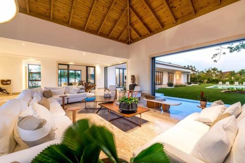 an open living room with white furniture and a large window at Casa Ceiba in La Romana