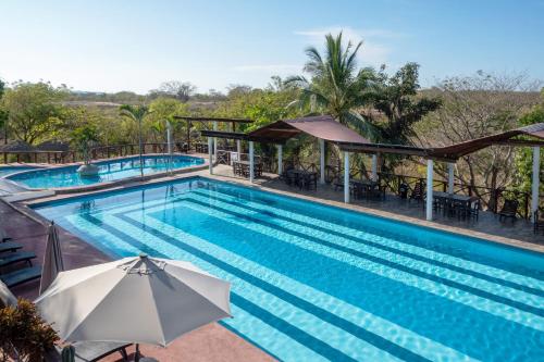 a pool at a resort with an umbrella at Casa Paraiso Hotel Boutique in Puerto Escondido