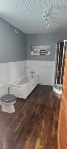 La salle de bains blanche est pourvue d'une baignoire et de toilettes. dans l'établissement Kanevedenn, à Val Couesnon