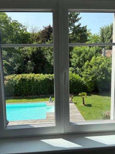 une fenêtre avec vue sur la piscine dans l'établissement La Parenthèse détente, à Muntzenheim