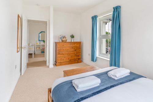 a bedroom with a bed with blue curtains and a dresser at Peaceful house 10 min walk to beach & parking in Falmouth