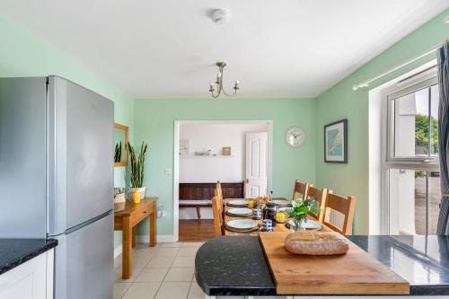 a kitchen and dining room with a table and refrigerator at Peaceful - 10-min walk to beach - The White House in Falmouth