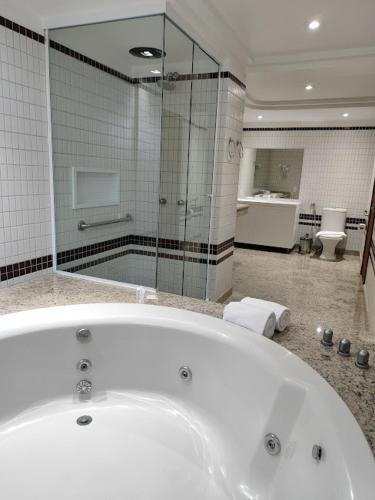 a bathroom with a bath tub and a shower at Alven Hotel by Slaviero Hotéis in Joinville