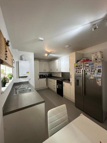 a kitchen with a stainless steel refrigerator and white cabinets at The XL modern retreat in London