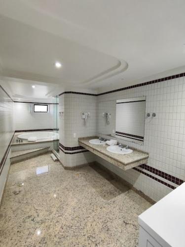 a bathroom with two sinks and a mirror at Alven Hotel by Slaviero Hotéis in Joinville