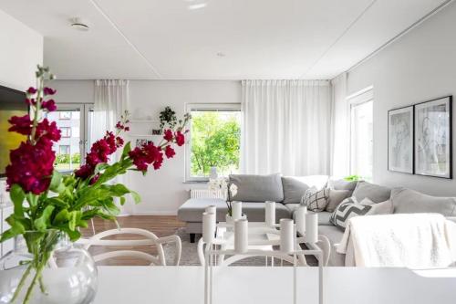 a living room with a couch and a table with red flowers at Appartment close to Hyllie in Klagshamn