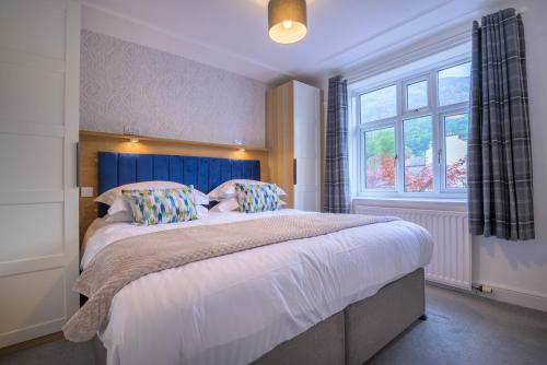 a bedroom with a bed with a blue headboard and a window at Moss Crag in Penrith