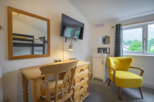 a bedroom with a desk and a yellow chair and a mirror at Moss Crag in Penrith