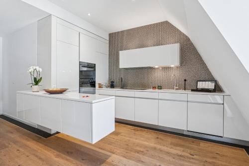 a kitchen with white cabinets and a large window at Horizon Home Löwenstrasse Penthouse in Zürich