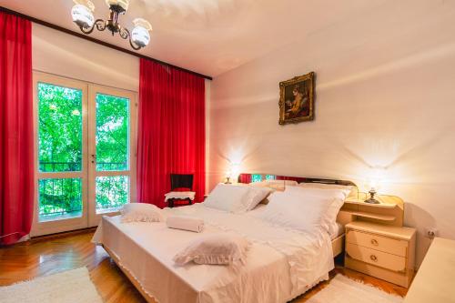 a bedroom with a large bed with red curtains at Kuća za odmor GOTA 