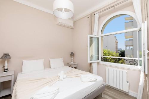 - une chambre avec un lit blanc et une fenêtre ouverte dans l'établissement JASMIN-Très chic 2 pièces, wifi, clim à 200 m Croisette, à Cannes