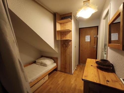 Cette petite chambre comprend un lit et une table en bois. dans l'établissement Résidence Chamoisiere - Grand studio à côté des pistes MAE-8504, à Montgenèvre