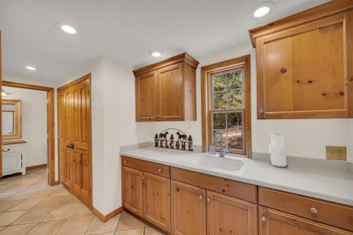 a kitchen with wooden cabinets and a sink and a window at Authentic log cabin minutes from Zion NP in Orderville