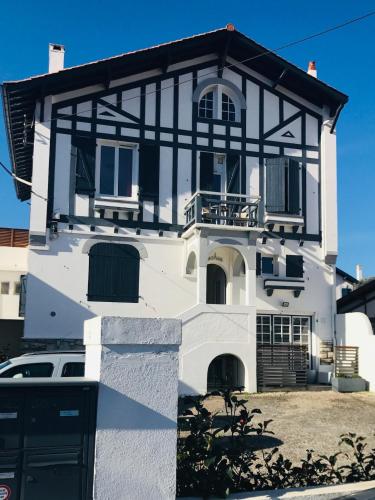 a white and black house with a car parked in front at Appartement Biarritz plage Milady surf in Biarritz