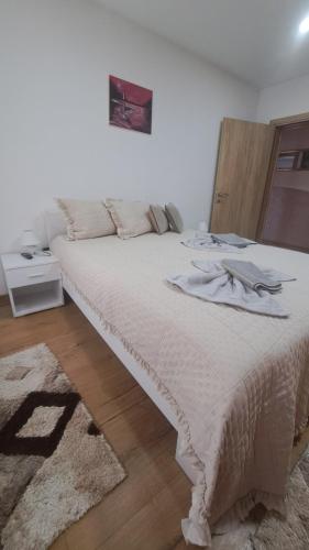 a bedroom with a large white bed with a rug at Apartman Nani in Bihać