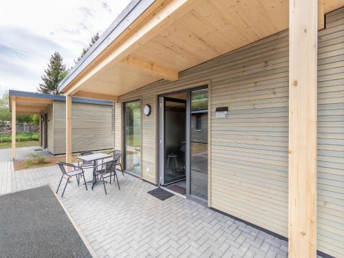 a patio with a table and chairs next to a house at Nice bungalow in Hallschlag near the lakebeach in Hallschlag
