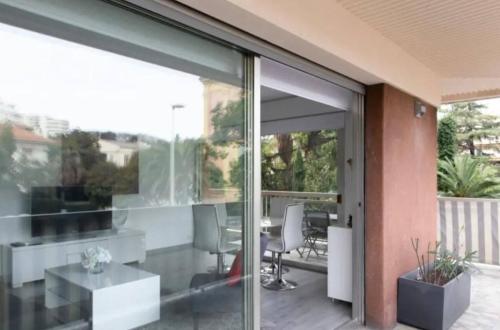 une porte vitrée ouverte d'une maison avec une table et des chaises dans l'établissement ESCURIAL Bel appart rénové proche Croisette et plage, à Cannes