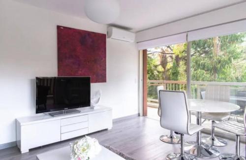un salon avec une télévision, une table et des chaises dans l'établissement ESCURIAL Bel appart rénové proche Croisette et plage, à Cannes