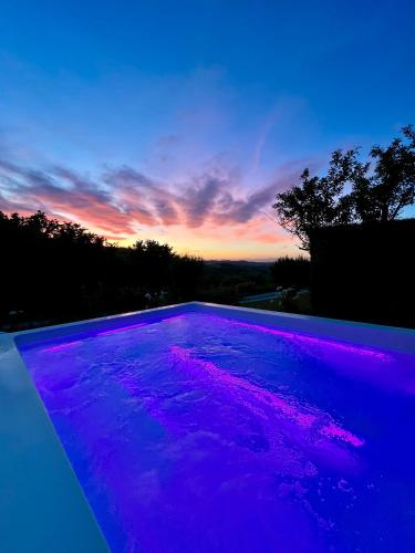 a purple swimming pool with a sunset in the background at MiaClara Relais in Alba
