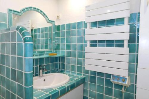 La salle de bains est pourvue de carrelage bleu, d'un lavabo et d'un miroir. dans l'établissement VINTAGE -Cosy nid douillet Vieil Antibes- Idéal couple, à Antibes