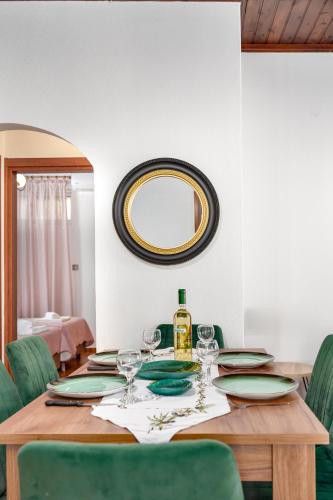 a dining room table with green chairs and a mirror at Villa Foteini Gerakari Mountain Resort in Yerakárion