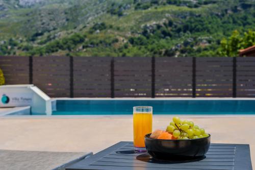 a bowl of fruit and a glass of juice on a table at Villa Foteini Gerakari Mountain Resort in Yerakárion