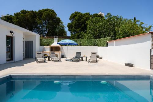 a swimming pool with chairs and an umbrella at Villa Foteini Gerakari Mountain Resort in Yerakárion