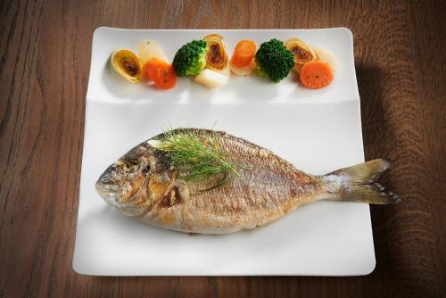 a fish on a plate with vegetables on a table at Pont du Chalon Hôtel and Restaurant in Margès