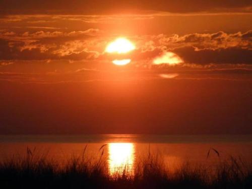 a sunset over the water with the sun in the sky at Apartment in Warin in der N he des Glammsees in Warin