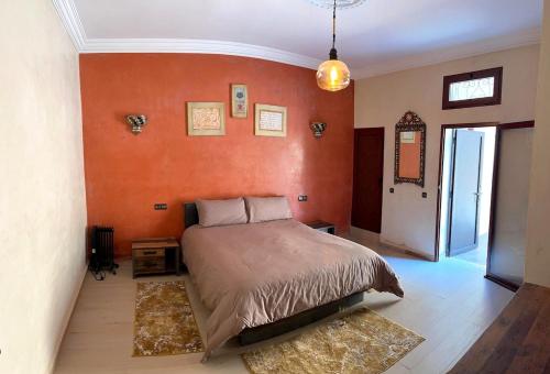 ein Schlafzimmer mit einem Bett und einer orangefarbenen Wand in der Unterkunft Intimate villa Private pool et Atlas view in Aït Bou Zguia