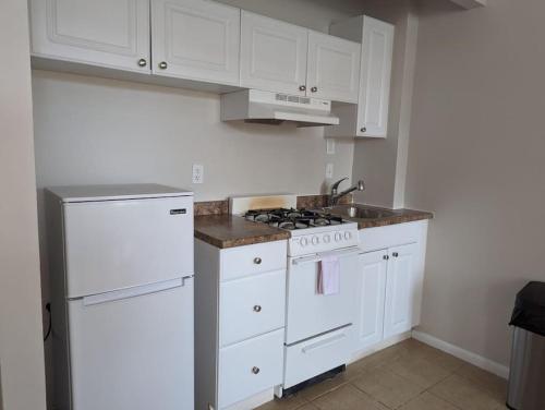 a white kitchen with a stove and a refrigerator at Urban Chic South End Studio in Boston