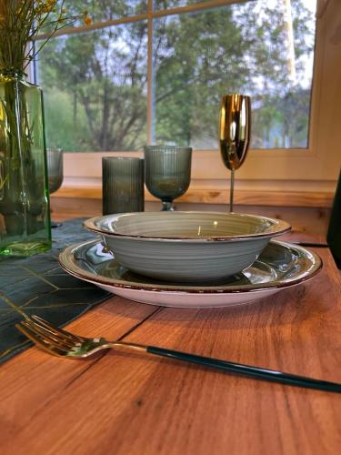 a table with a plate and two wine glasses on it at Файна хата 4 in Synevyrsʼka Polyana