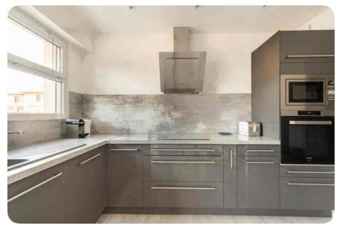 d'une cuisine équipée d'appareils en acier inoxydable et d'une fenêtre. dans l'établissement ETOILE Cosy 2 p, tout confort, 10 min Croisette, à Cannes