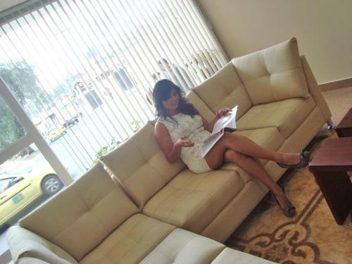 a woman sitting on a couch reading a book at Hotel de las Américas - Ambato in Ambato