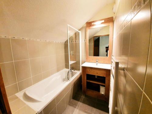 une salle de bain avec une baignoire, un lavabo et un miroir dans l'établissement Les Chalets Des Rennes - Appartement 3 pièces - Les Chalets Des Rennes MAE-9604, à Vars