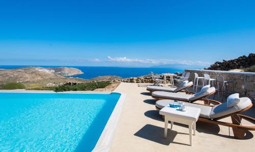 a pool with lounge chairs and a view of the ocean at Amallini Suites Mykonos in Super Paradise Beach