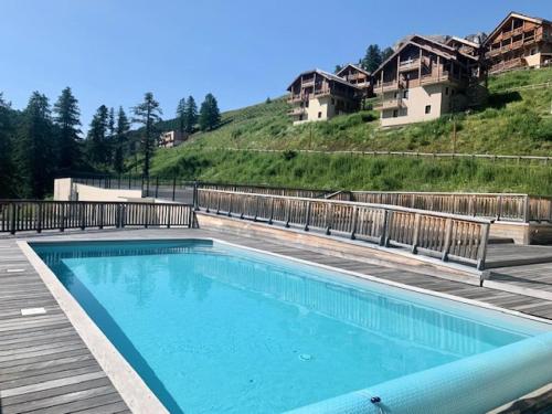 une piscine sur une terrasse avec des maisons en arrière-plan dans l'établissement Les Chalets Des Rennes - Appartement moderne 2P4 - Les Chalets Des Rennes MAE-6551, à Vars