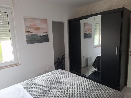 a bedroom with a large black cabinet with a mirror at Apartment Riverside in Metković