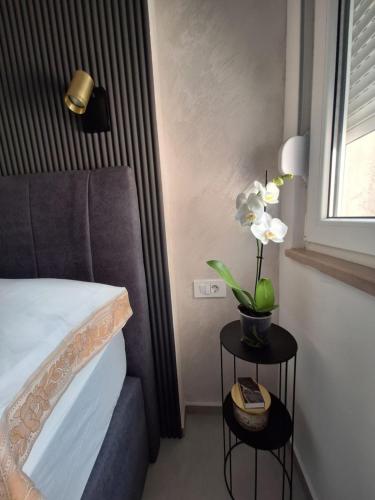 a bedroom with a bed and a table with flowers on it at Apartment Riverside in Metković