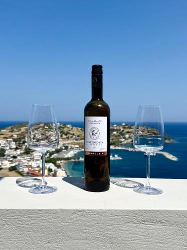 a bottle of wine and two wine glasses on a ledge at PETRA Luxury Villas in Áyioi Apóstoloi