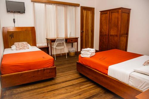 two beds in a room with a desk and a desk at Luz de Luna Escalante in San José