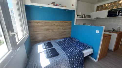 a small bedroom with a bed with blue walls at Ô Cosy Studio in La Grande-Motte