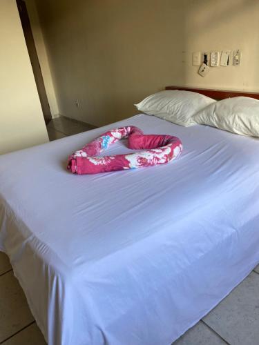 a pink blanket laying on top of a bed at Quarto Econômico no Centro para 2 Pessoas in Sete Lagoas