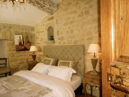 a bedroom with a bed and a stone wall at Un Patio en Luberon in Ansouis